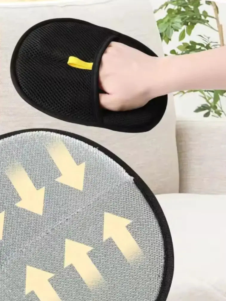 Black slippers with yellow accents held by a hand on a light-colored couch.