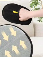 Black slippers with yellow accents held by a hand on a light-colored couch.