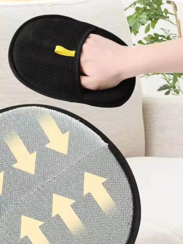 Black slippers with yellow accents held by a hand on a light-colored couch.